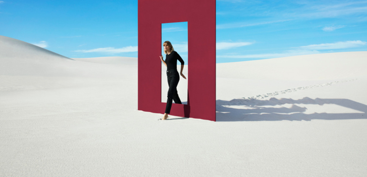 Frau geht durch Tür, auf Sand mit blauem Himmel