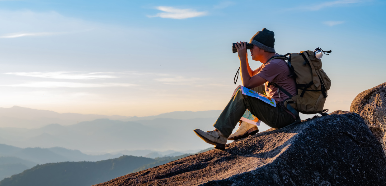 Mann auf Felsen mit Fernglas